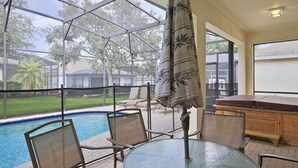Ein überdachter Außenbereich mit Pool, Stühlen und Tisch.