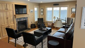 A living room with a fireplace, a television, a sofa, and a coffee table. - Ski In/Ski Out Mountain Top Condo at Crystal Mountain (Thompsonville)