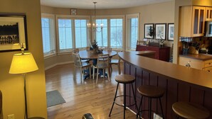 A modern kitchen with a dining area, large windows, and a bar counter. - Ski In/Ski Out Mountain Top Condo at Crystal Mountain (Thompsonville)