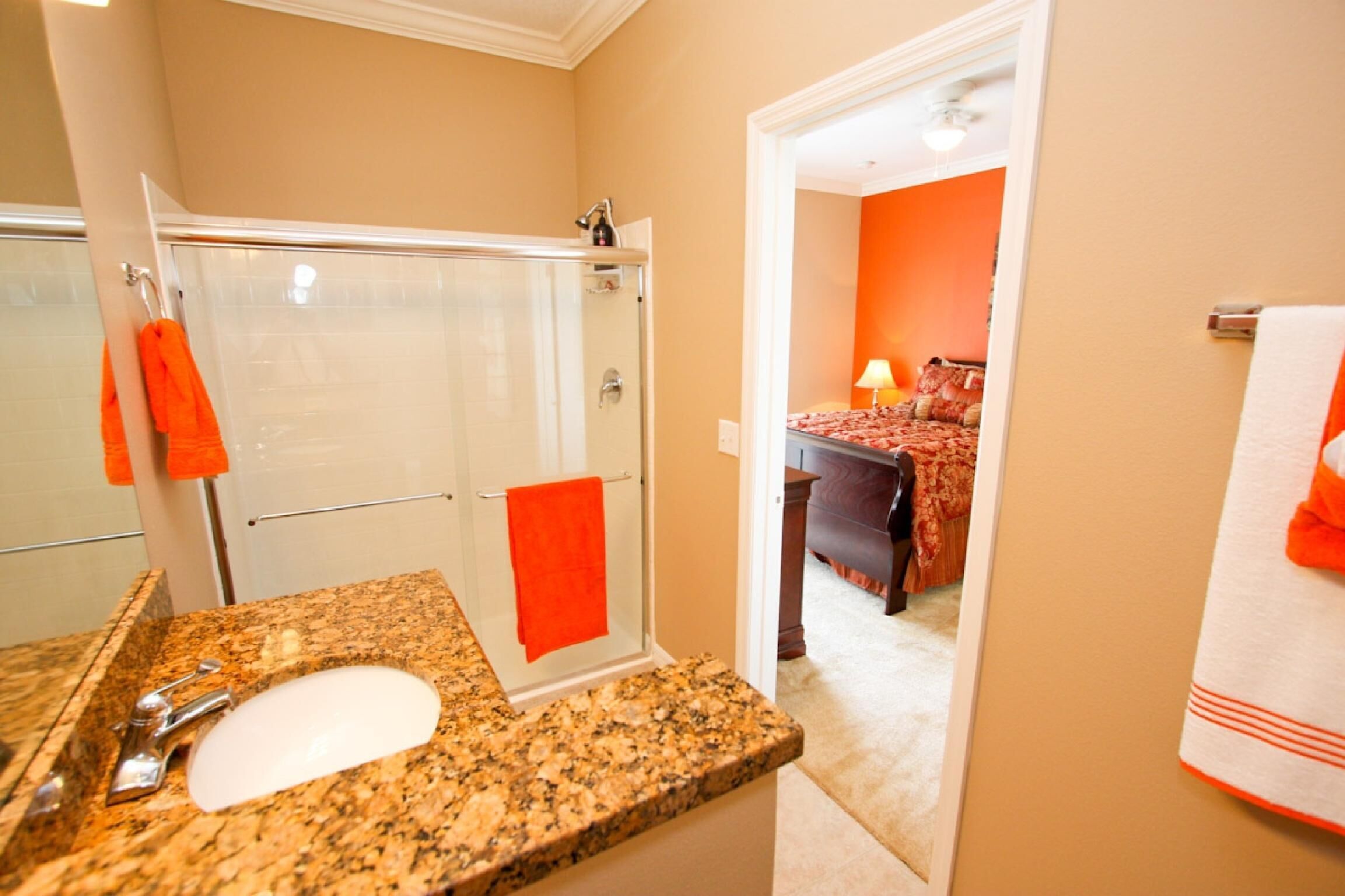 A bathroom with a granite countertop, a white sink, and a glass shower enclosure.