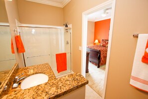 A bathroom with a granite countertop, a white sink, and a glass shower enclosure. - 1531 Dream (Clermont)