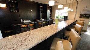 A bar area with a granite countertop, bar stools, and a wine cooler. - 3081 Encantada (Kissimmee)
