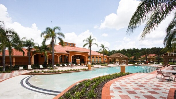 Ein Resort mit großem Pool, Palmen und einer gefliesten Terrasse.