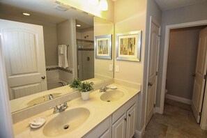 A bathroom with two sinks, a large mirror, and framed artwork on the wall. - 4201 Solterra (Davenport)
