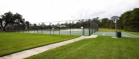 Ein Basketballplatz im Freien mit Zaun, Mülleimer und Korb.