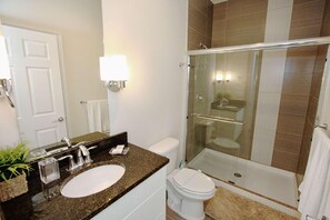Ein Badezimmer mit Marmorwaschtisch, Toilette in Weiß, einer Duschkabine und einer weißen Tür.