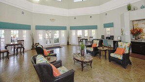 Eine großzügige Lobby mit hoher Decke, mehreren Sitzbereichen und großen Fenstern, die für viel Tageslicht sorgen.