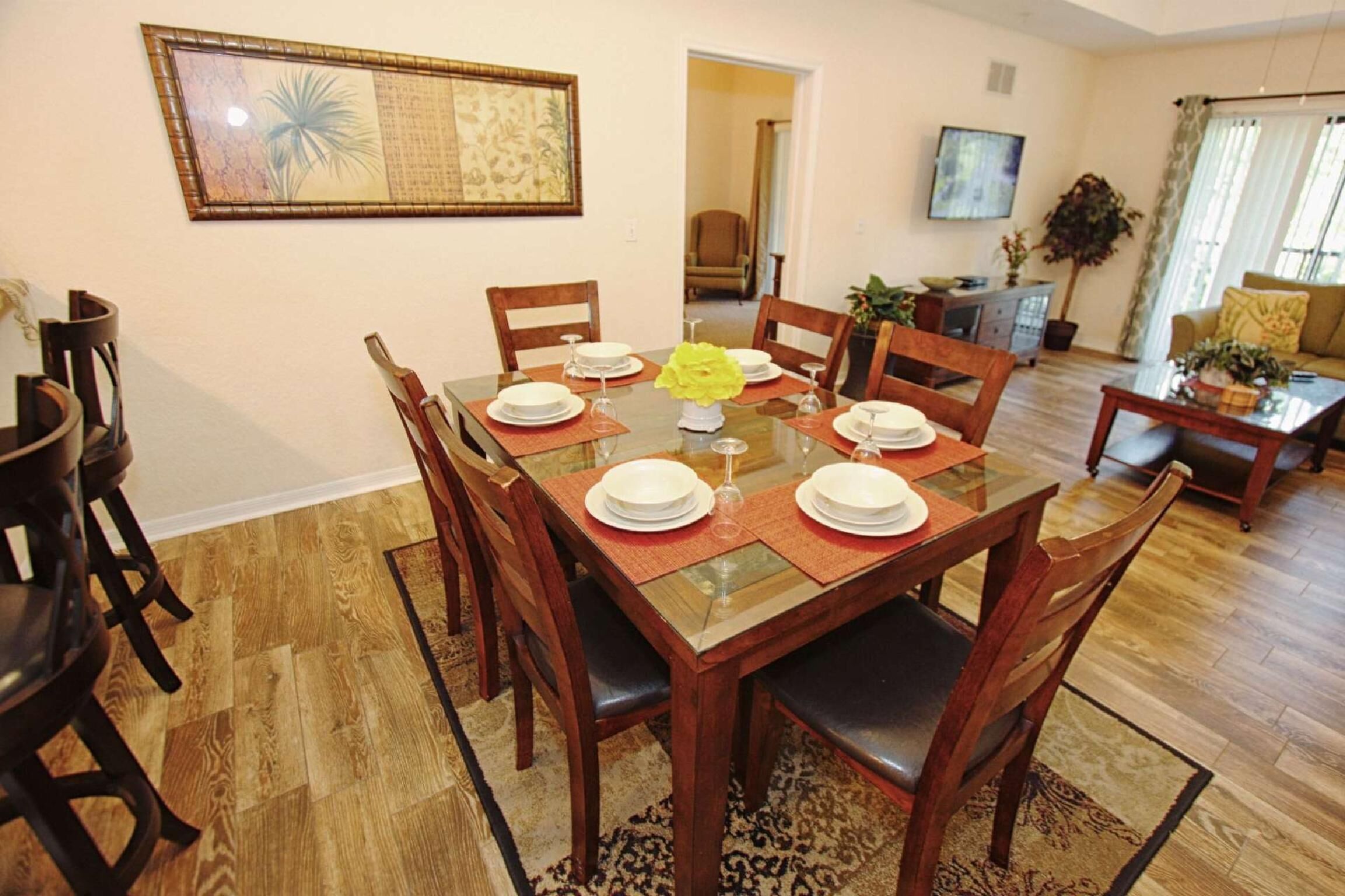 Comedor con mesa de madera dispuesta para cuatro personas, rodeada de sillas.