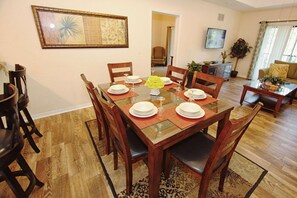 A dining area with a wooden table set for four, surrounded by chairs. - 3060 Caribe Cove (Kissimmee)