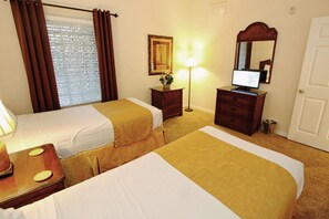 A hotel room with two beds, a desk with a computer, a lamp, a dresser, and a mirror. - 3060 Caribe Cove (Kissimmee)