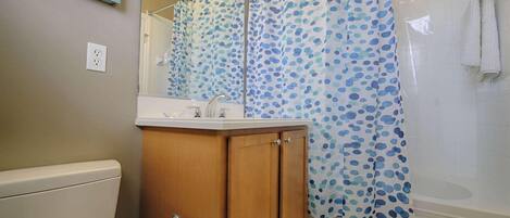 Un bagno con un armadietto in legno, un water, un lavandino e una doccia con tenda a pois.