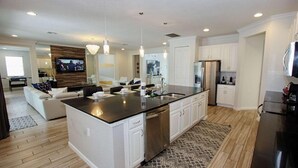 A modern kitchen with a central island, white cabinetry, stainless steel appliances, and pendant lighting. - 3941 Sonoma (Kissimmee)