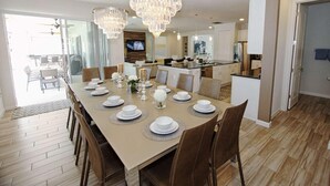 A dining area with a long table set for a meal, surrounded by chairs. - 3941 Sonoma (Kissimmee)