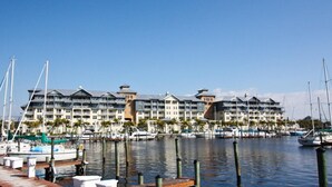 A marina with multiple boats docked, a waterfront hotel with balconies, and a clear blue sky. - 565 Little Harbor (Ruskin)