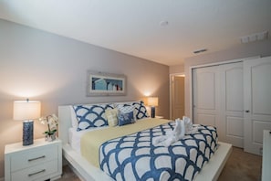 A neatly arranged bedroom with a bed, bedside tables, and a door.