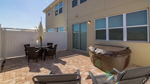 A patio area with a table and chairs, a hot tub, and a covered seating area. - 5133 Compass Bay (Kissimmee)