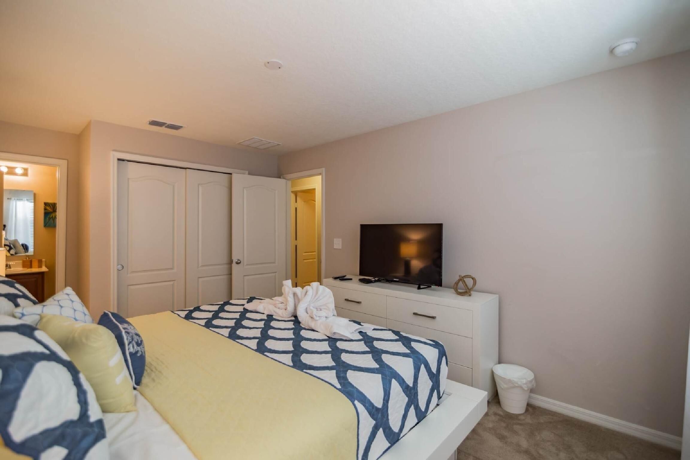 A hotel room with a bed, a television, a dresser, and a closet.