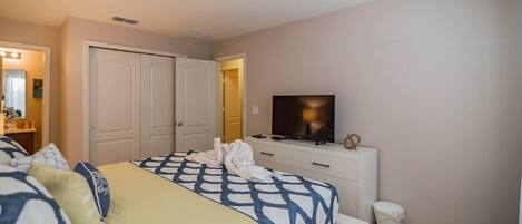 A hotel room with a bed, a television, a dresser, and a closet.