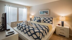 A bedroom with a bed, bedside tables, a desk with a computer, and a TV. - 5133 Compass Bay (Kissimmee)