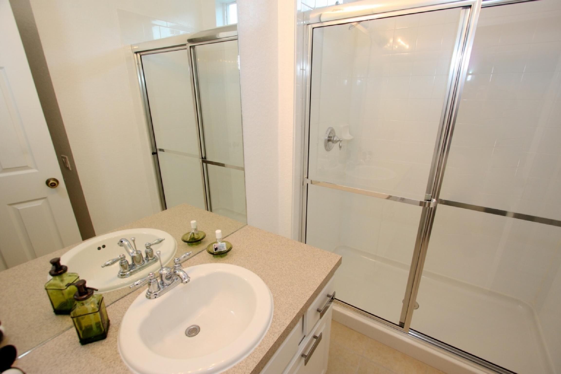 A bathroom with a white sink, two mirrors, and a glass shower enclosure.