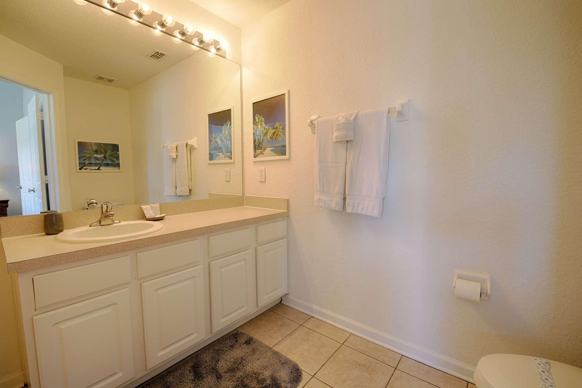Une salle de bain équipée d’un lavabo, d’un miroir et d’un porte-serviettes.