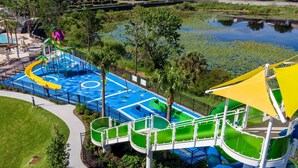 Ein Wasserpark mit Rutschen und Pools, umgeben von Grünflächen und einem See.