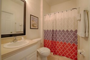 A bathroom with a sink, toilet, and shower curtain. - 7676 Windsor Hills (Kissimmee)