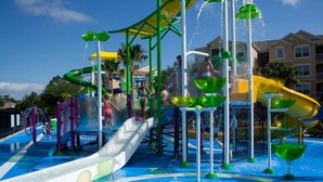 Ein Wasserpark mit Rutschen, Spritzbereichen und einem überdachten Bereich.