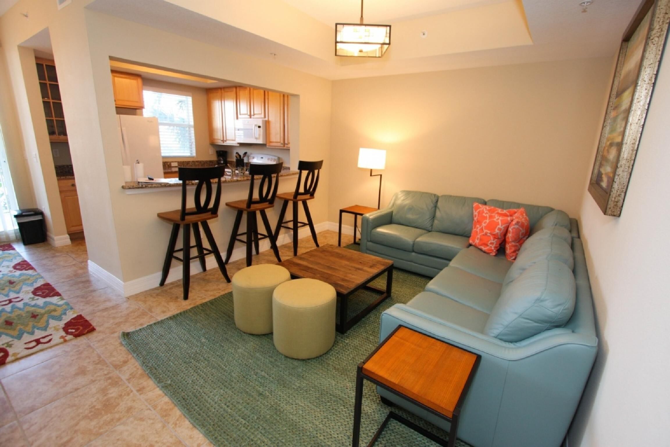 A living room with a sofa, ottomans, a coffee table, and a dining area with chairs and a table.