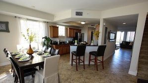 A spacious kitchen with wooden cabinets, a dining area with a table set for four, and a living area with a sofa and a coffee table. - 579 Little Harbor (Ruskin)