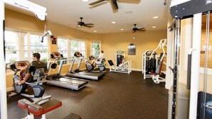 Ein Fitnessraum mit Laufbändern, Kraftgeräten und Deckenventilatoren.