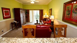 A living room with a red leather sofa, a wooden coffee table, and a ceiling fan. - 709 Bahama Bay (Davenport)