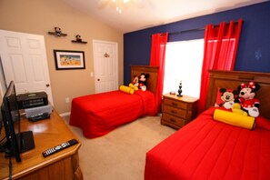 A bedroom with two beds, a desk, and a dresser.