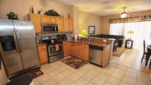 A kitchen with wooden cabinets, stainless steel appliances, and a central island. - 7669 Windsor Hills (Kissimmee)