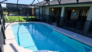 A swimming pool with a glass enclosure, a covered patio area, and a view of the backyard. - 217 Legacy Park (Davenport)