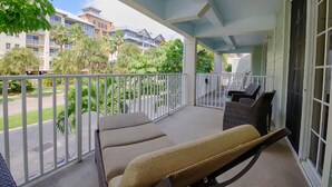 Ein Balkon mit zwei gepolsterten Stühlen, einem kleinen Tisch und einem Grill.