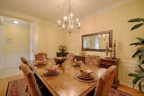 A formal dining room with a wooden table, patterned chairs, a chandelier, and a mirror on the wall. - 5048 Vista Cay (Orlando)