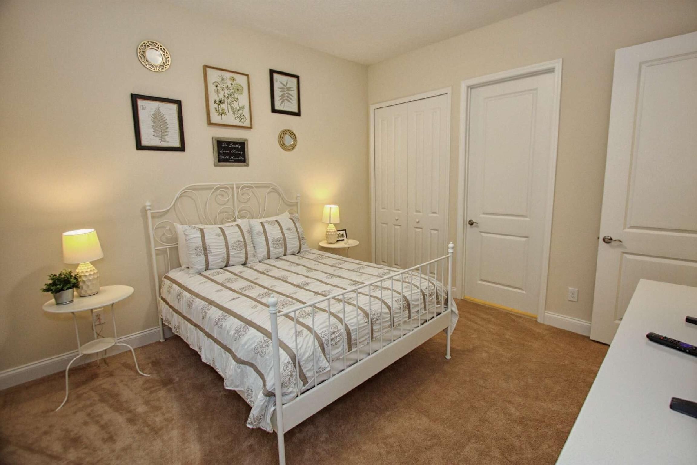 Quarto com cama, duas mesas de cabeceira e uma porta.