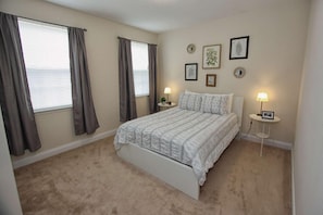 A bedroom with a bed, two bedside tables, and a window with curtains.