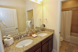 A bathroom with two sinks, a large mirror, a towel rack, and a shower curtain.