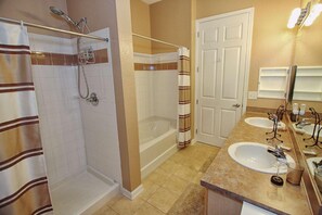 A bathroom with a shower, a bathtub, two sinks, and a door. - 721 Terrace Ridge (Davenport)