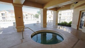 A covered swimming pool area with lounge chairs and a view of residential buildings. - 721 Terrace Ridge (Davenport)