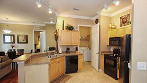 A modern kitchen with wooden cabinets, a dishwasher, a refrigerator, and a microwave. - 721 Terrace Ridge (Davenport)