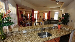 A kitchen with granite countertops, a stainless steel sink, wooden cabinets, and a dining area in the background. - 721 Terrace Ridge (Davenport)