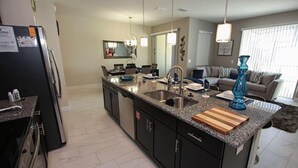 A modern kitchen with granite countertops, a stainless steel sink, and a black refrigerator. - 4888 Storey Lake (Kissimmee)