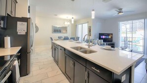 Una cucina moderna con una grande isola, elettrodomestici integrati e un'area pranzo con televisore.