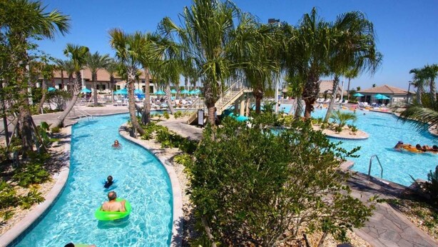 Area piscina di un resort con diverse piscine, palme e lettini.