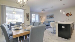 Un soggiorno moderno con angolo pranzo, cucina e un'ampia finestra che permette l'ingresso di luce naturale.