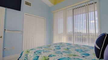 A bedroom with a bed, a window with blinds, a door, and a ceiling vent.