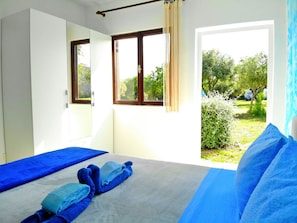Een slaapkamer met twee bedden, een raam met gordijnen en uitzicht op groen.